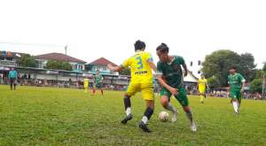 Pemain tengah Beringin Serut, Reza (nomor 3) mendrible bola berusaha melewati penyerang Bunga Mekar, Rifki (hijau). Beringin Serut unggul 2-0 atas Bunga Mekar.