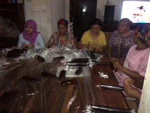 Ci IIn (pakai baju kuning) bersama beberapa karyawannya sedang menggulung dodol