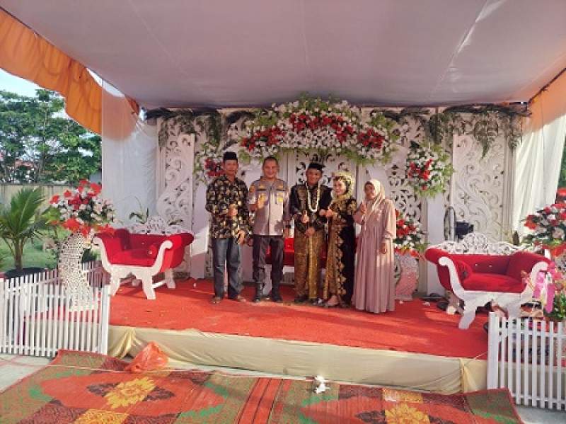 Kapolsek AKP Krisnat berfoto bersama pasangan pengantin, Ridho dan Ayu Syahfitri, yang melangsungkan resepsi pernikahan di halaman Mapolsek Kualuh Hilir di Tanjung Leidong Kecamatan Kualuh Leidong Kabupaten Labura.