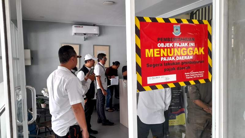 Petugas gabungan dari Pemkot Tangsel saat mendatangi hotel Reddoorz, nampak stiker warna merah bertuliskan pemberitahuan obyek pajak menunggak pajak terpasang di kaca pintu masuk hotel Reddoorz.