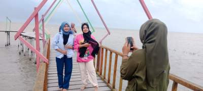 Pengunjung foto selfie di tracking menuju laut di pantai Cemara Kembar.