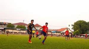 Pemain Ponser, Alam (jersey merah) hadang bola yang mengarah ke pemain Porba City, Jabrix (jersey hijau) dalam laga 32 besar Pakujaya Cup 8 di Stadion Mini Pakujaya, Serpong Utara.