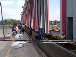 Petugas saat sedang menurunkan karung pasir untuk menutup kebocoran di pintu 6